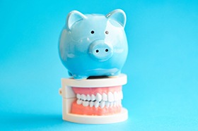 Cost of dental implants in Marshall represented by piggy bank atop model teeth