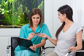 Woman handing over card to pay for dental treatment