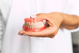 A close-up view of a hand holding dentures in Marshall