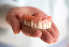 A close-up of a hand holding dentures