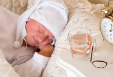 A man sleeping while his dentures are on the nightstand