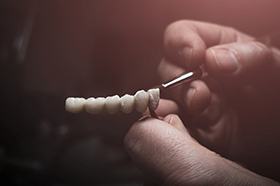 Lab technician painting replacement teeth