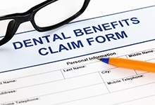 Dental benefits claim form with pen and glasses