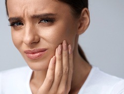 Woman touching face, concerned about possible failed dental implant