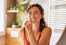 Woman practicing good oral hygiene after dental implant surgery