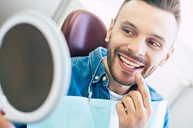 Man with veneers in Marshall smiling in dentist's mirror