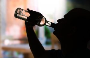 A person drinking from an alcohol bottle