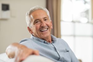 an older man sitting on a couch smiling