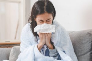 Woman on couch sneezing during cold and flu season