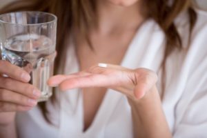 woman taking antibiotic pill before a tooth extraction