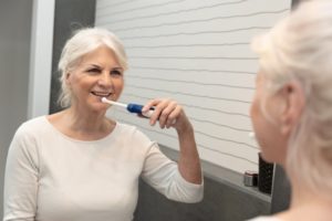 Senior woman cleaning dentures while they’re in her mouth