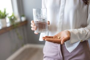 Woman holding pill, wondering, “Is sedation dentistry covered by insurance?”