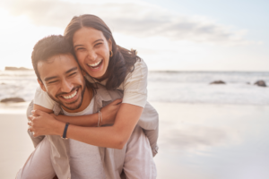 a happy couple smiling while visiting the beach