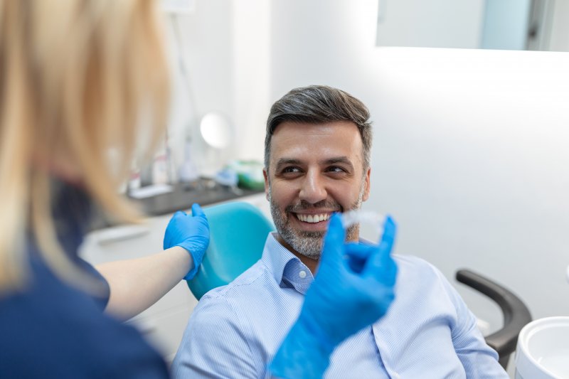 A younger man smiling after getting dentures