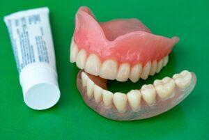 Dentures and adhesive on a green background